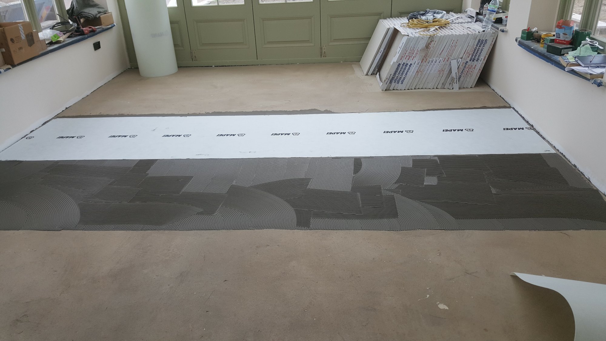 The primed subfloor was covered with adhesive as the anti-fracture membrane was installed across the kitchen and dining area.
