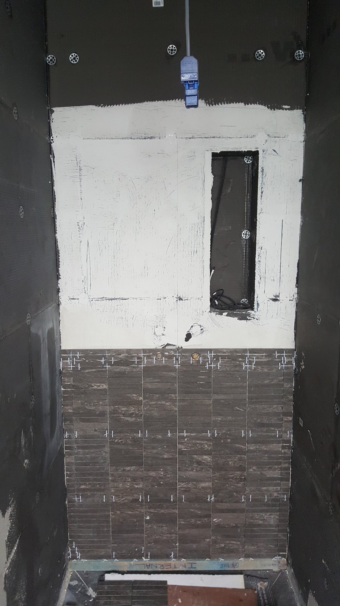 The prepared and waterproofed shower wall was carefully tiled, with a recessed storage niche incorporated into the design.