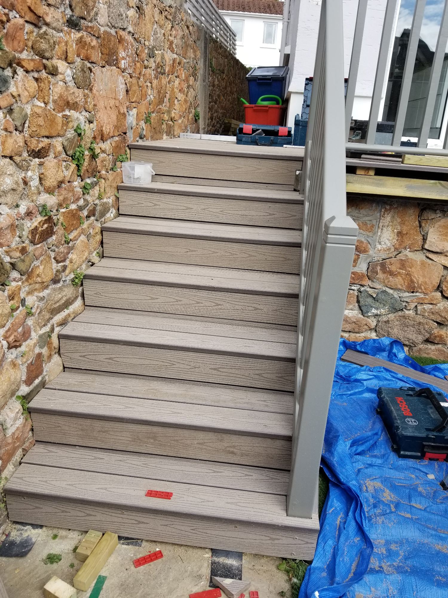 Treppenmontage im Fortschritt
Detailansicht der neu belegten Stufen aus Verbundwerkstoff und des farblich passenden grauen Geländers.