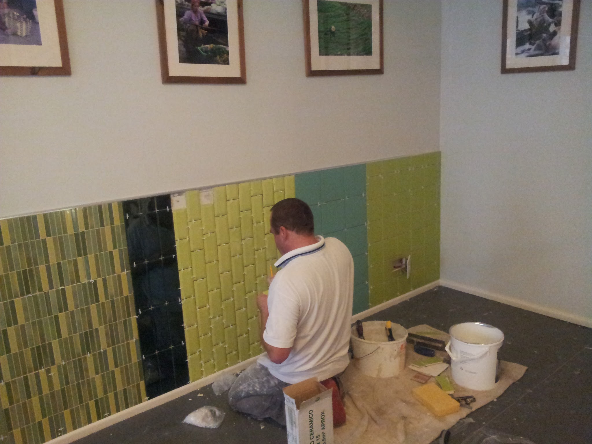Precision work during the installation of the feature wall. The combination of smooth, glossy, textured and mosaic tiles creates depth and visual variety.