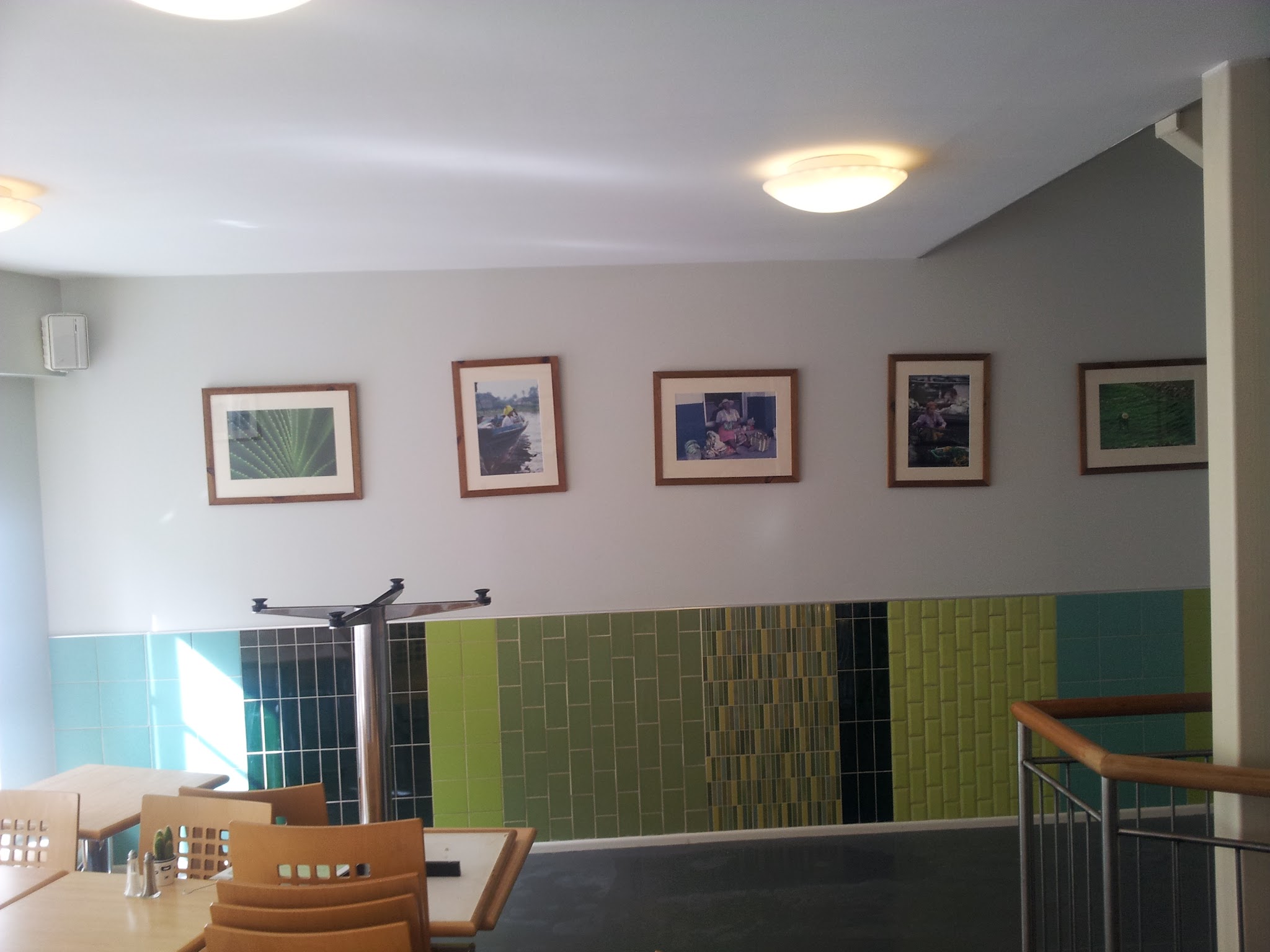 A wider view of the finished installation within the café interior. The different tile formats form a continuous decorative composition across the length of the wall.