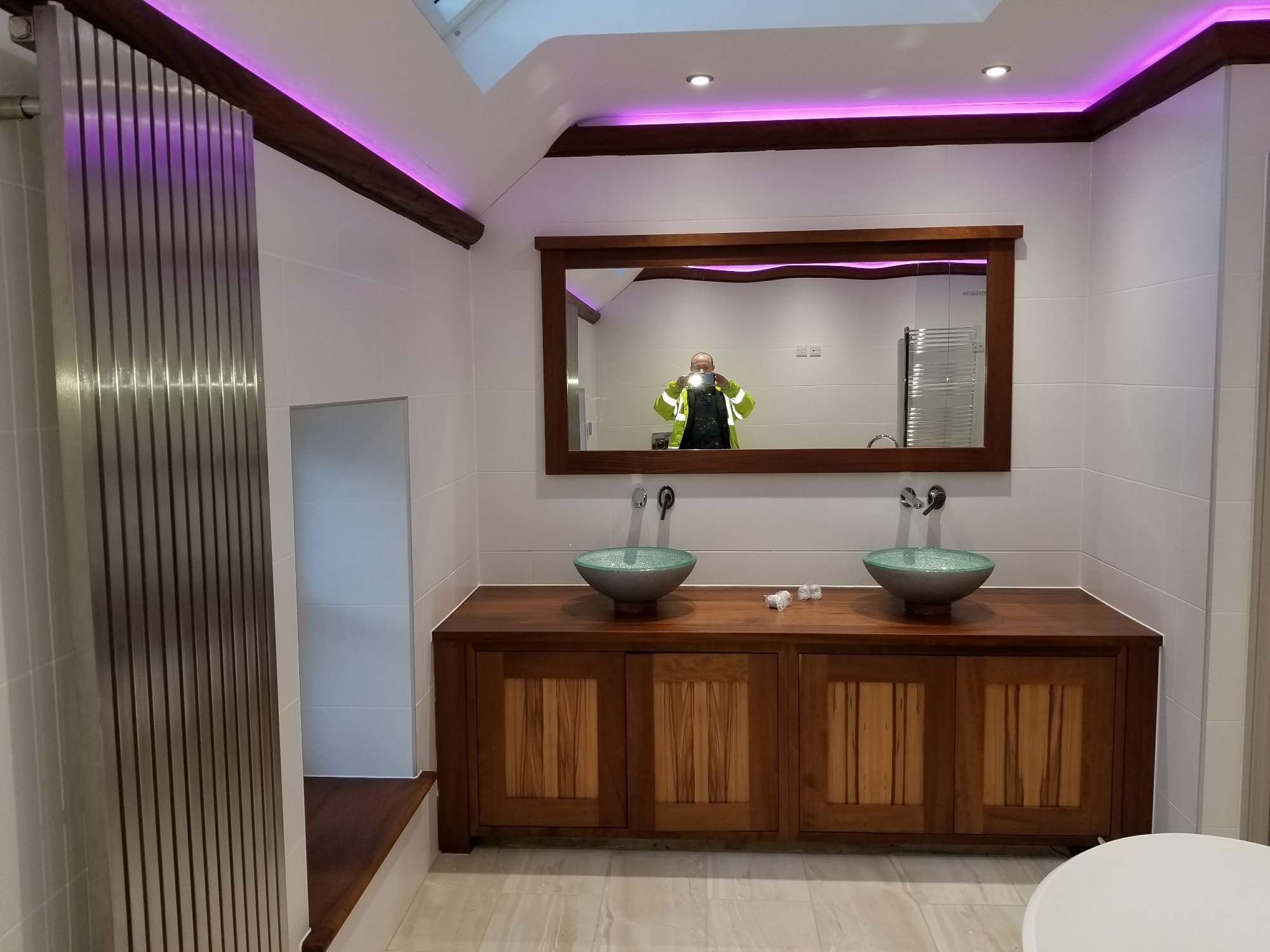 A custom wooden vanity unit, large framed mirror and two glass washbasins create a practical and elegant focal point.