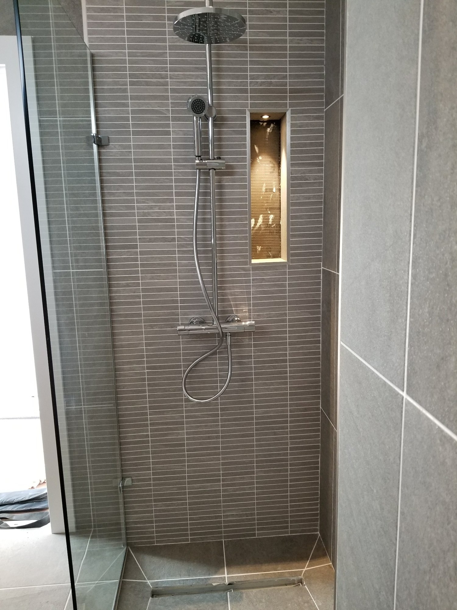 A chrome rainfall shower system and illuminated storage niche provide both comfort and practical storage.