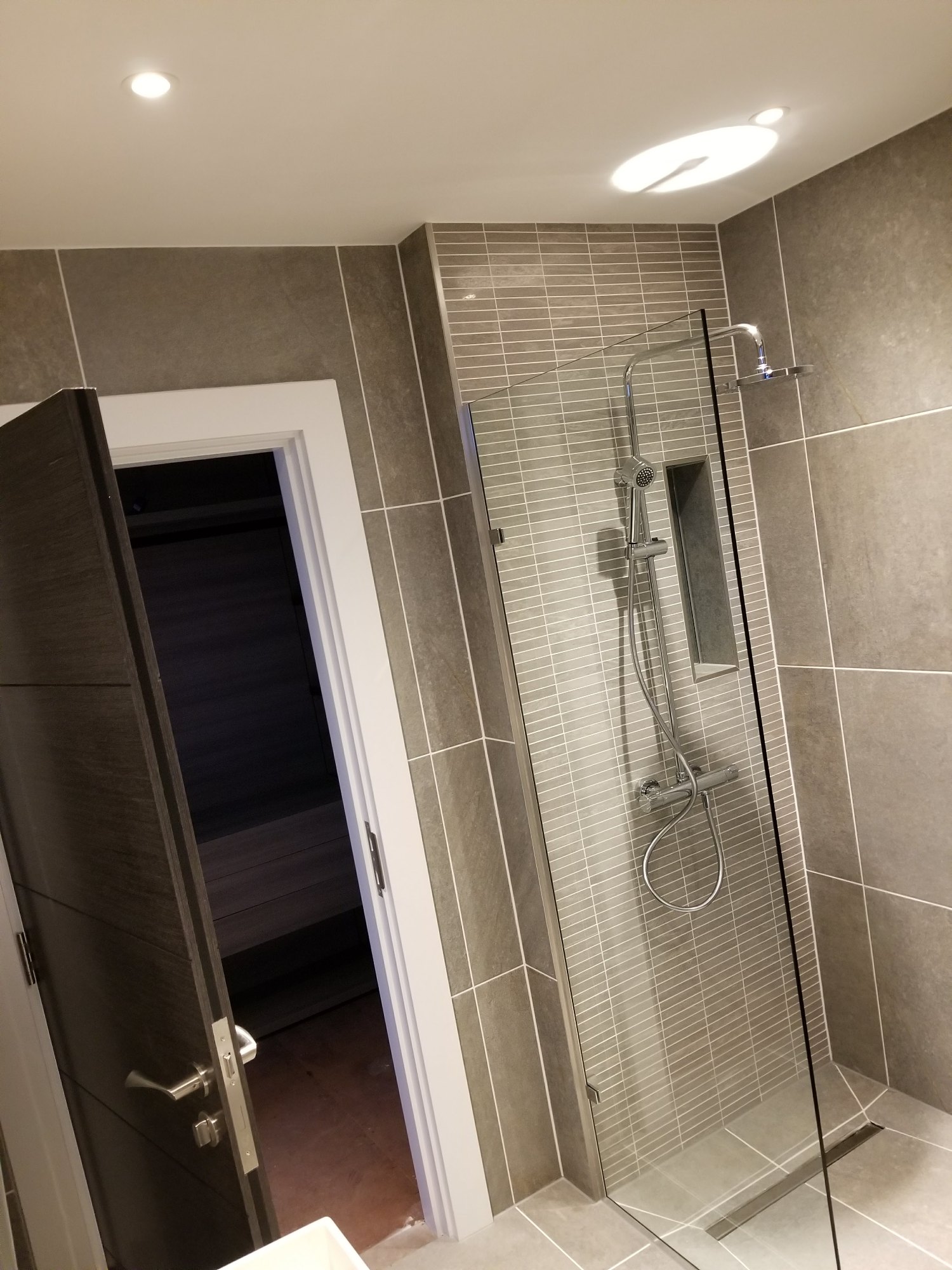 The frameless glass screen preserves the room’s bright and open appearance while separating the wet area