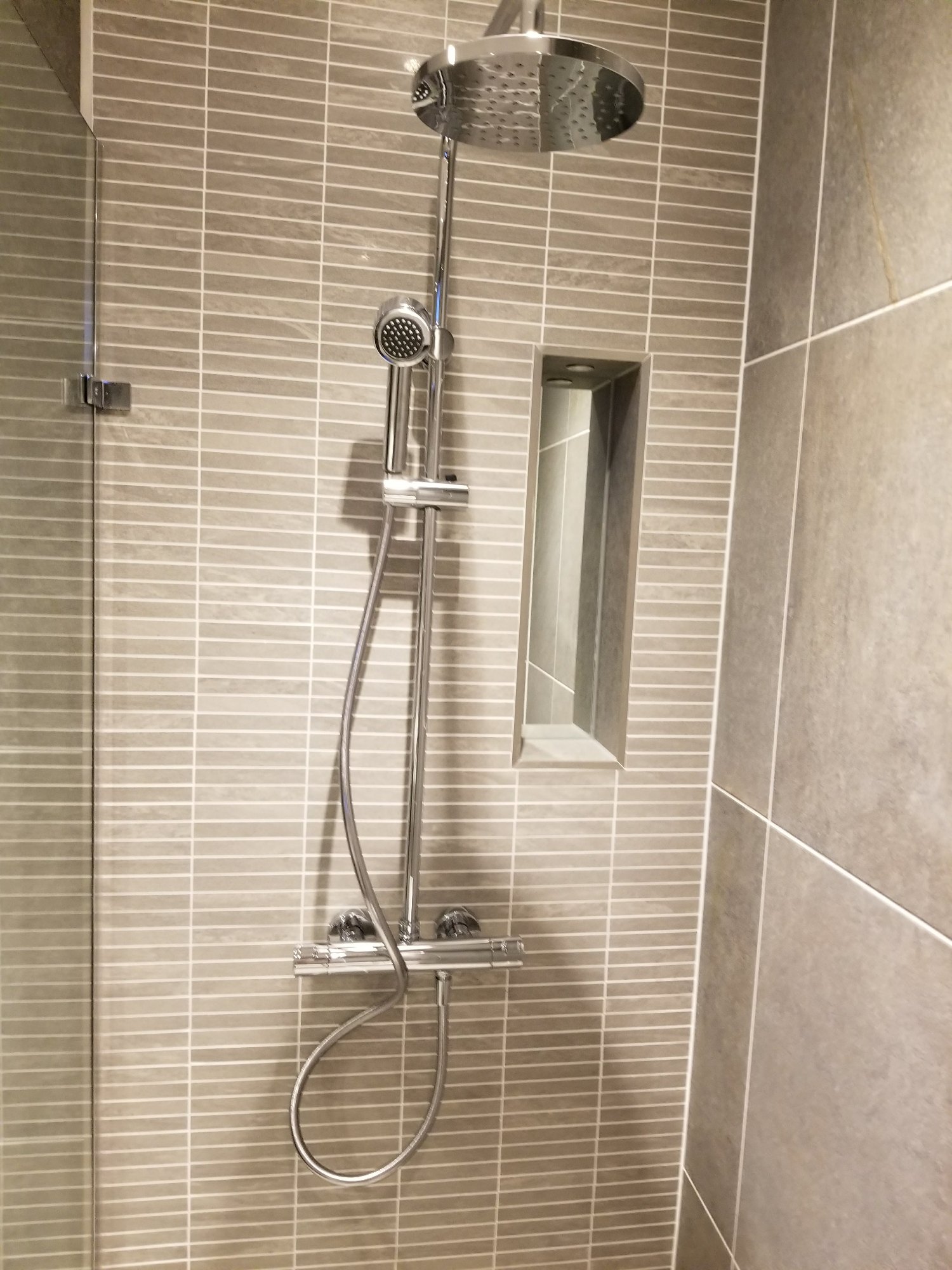 Light grey tiles, chrome fittings and the recessed shower niche create a coordinated and contemporary finish.