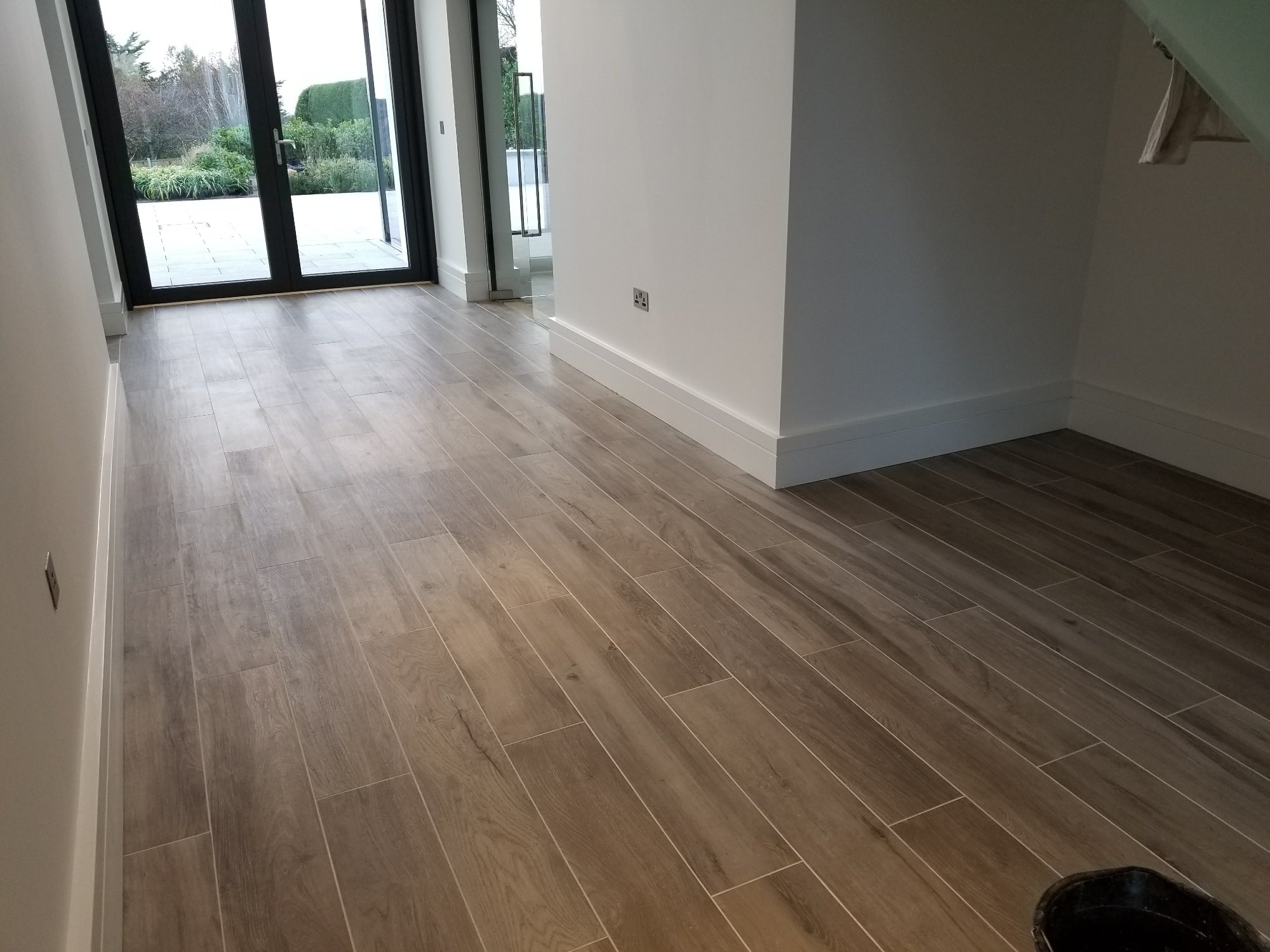 Precisely aligned wood-effect tiles provide a durable surface while visually extending the interior towards the garden.