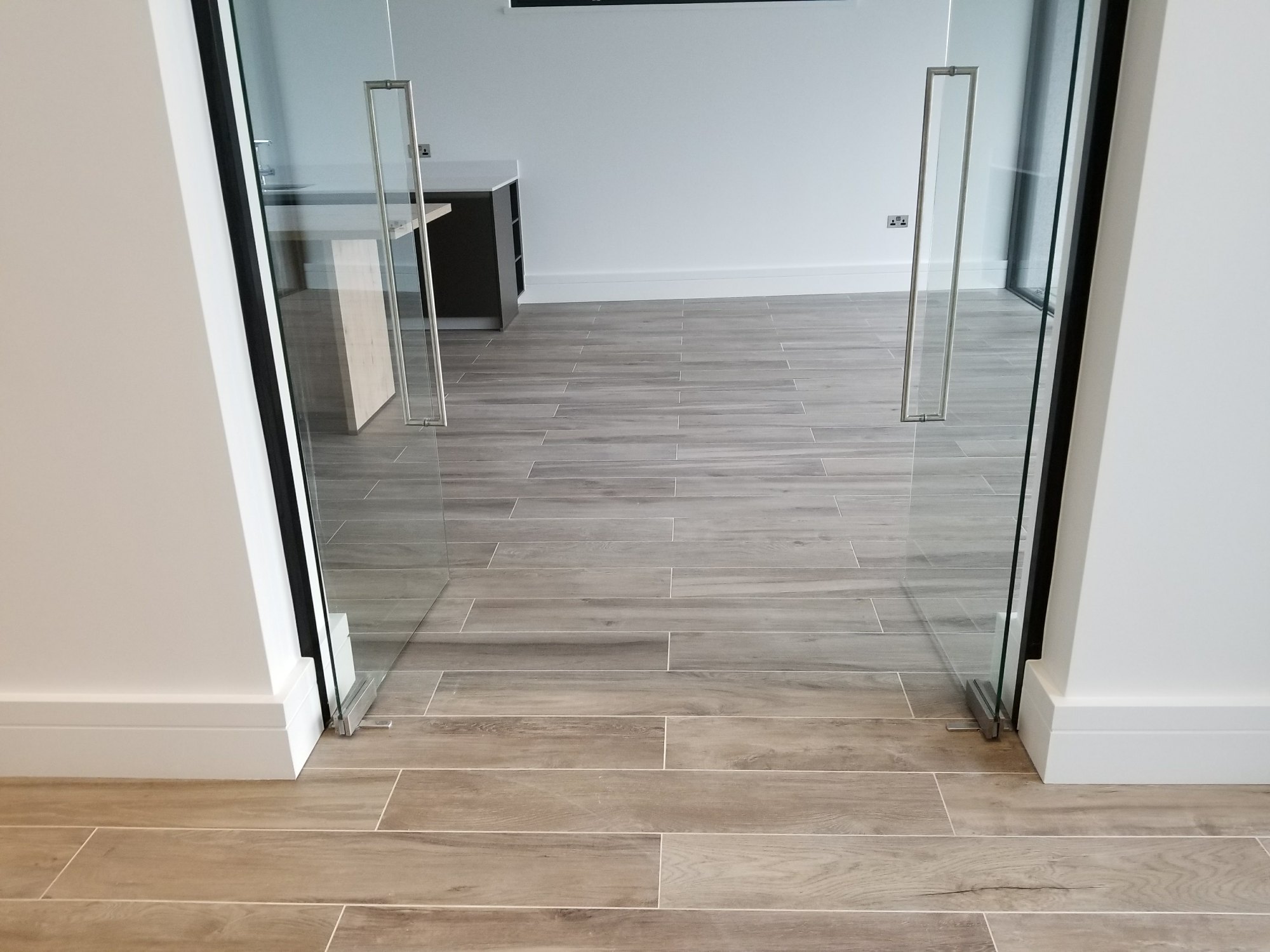 The same flooring continues without interruption through the glass doors, connecting the different living spaces.
