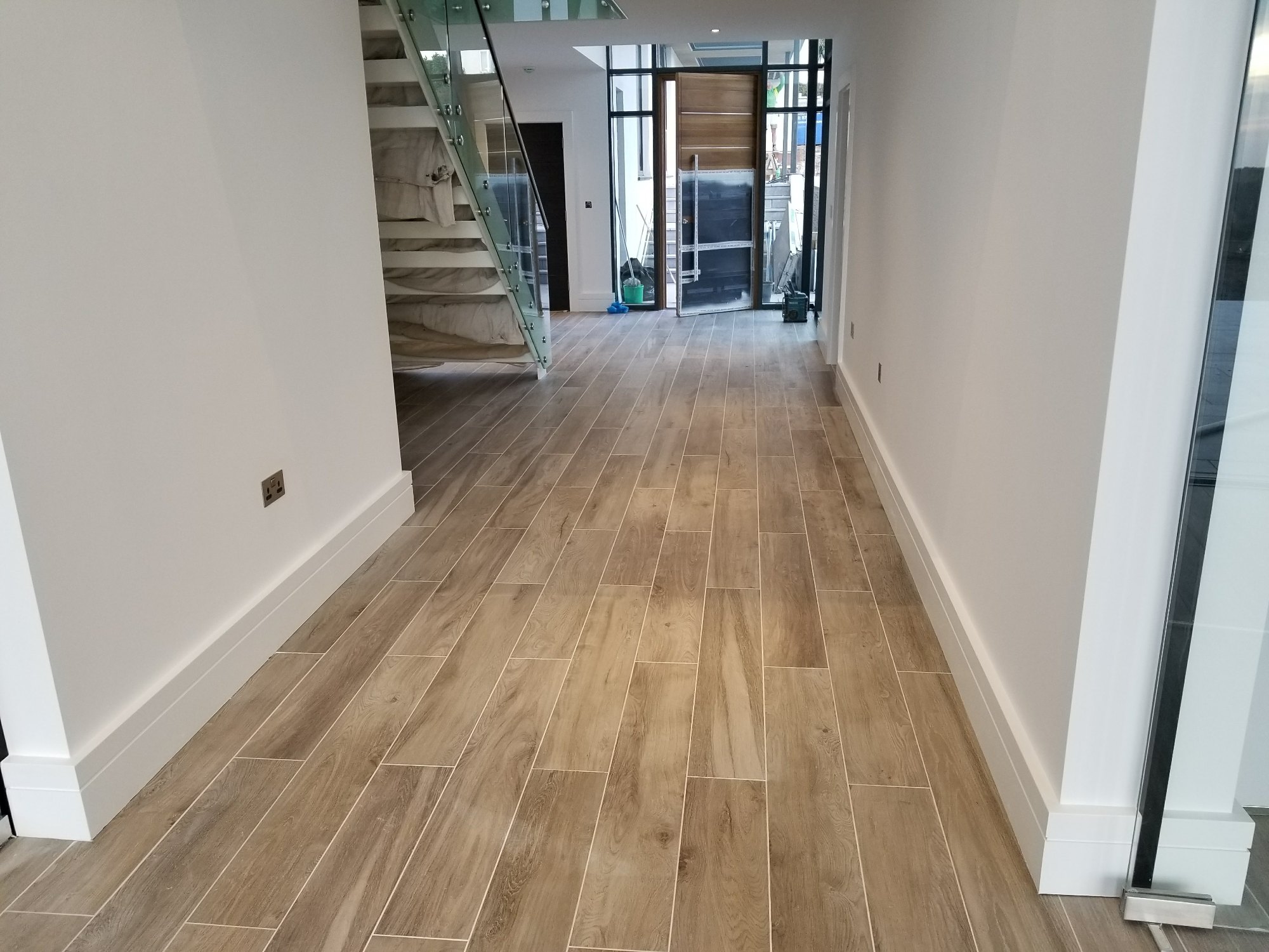 A wider view shows the continuous tiled floor extending through the hallway, kitchen and dining area for a cohesive finish.
