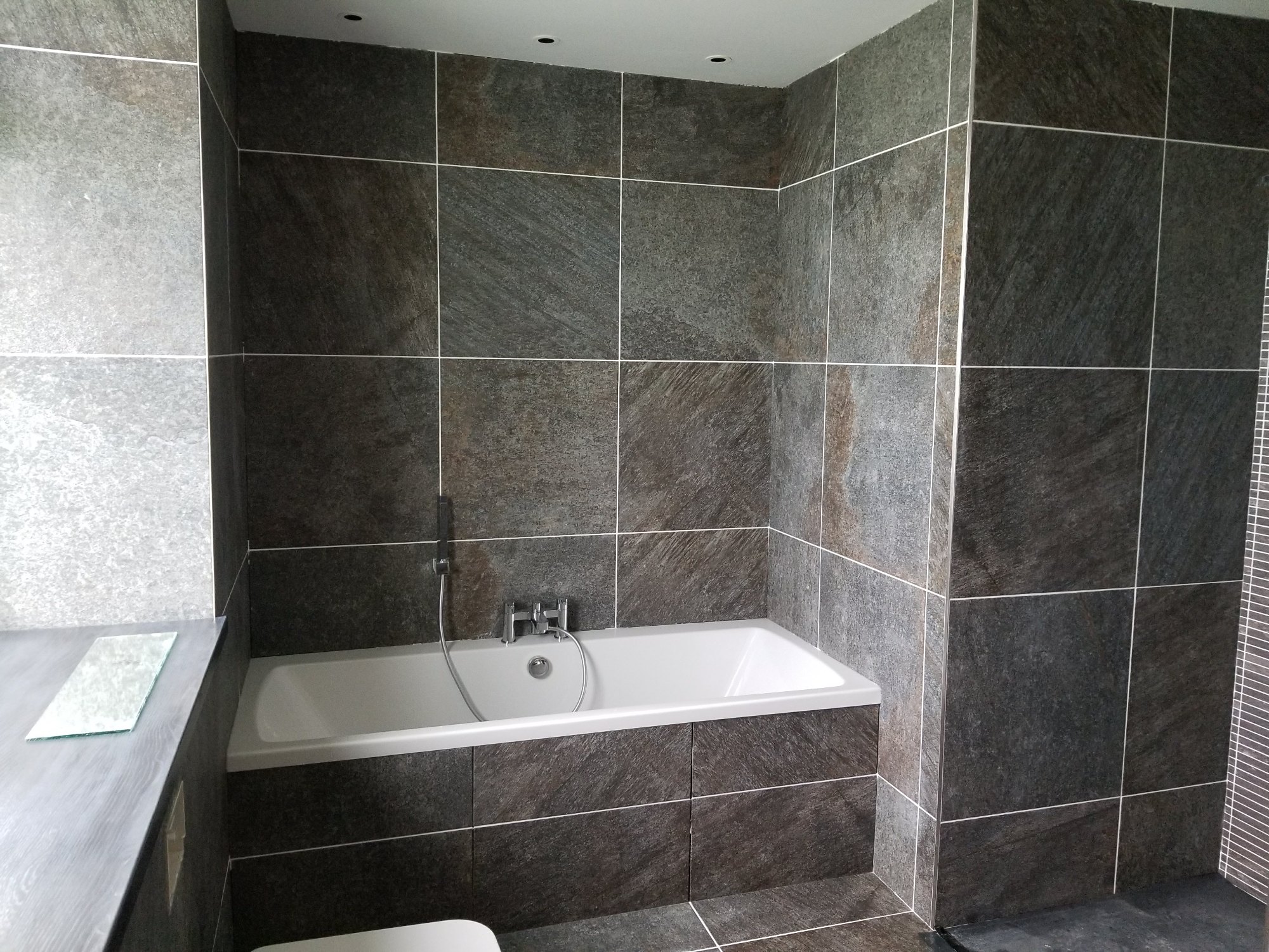 The fitted bath was finished with large-format stone-effect tiles, creating a seamless and durable surround.